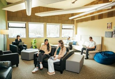 Bright communal lounge area with comfortable black sofas and large windows.