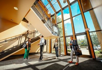 Bright, modern multi-story lobby with large windows and students or professionals talking.