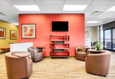 Lounge area with brown tub chairs, a coral feature wall, and a television.