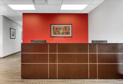 Wooden reception desk against a bright red feature wall with a framed picture.