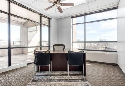 Private office with large windows, dark wood desk, and ceiling fan.