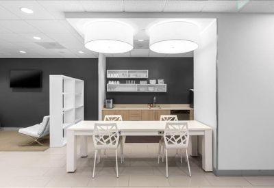 Bright communal kitchen area with a white dining table and decorative chairs.