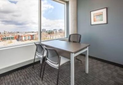 Private corner office featuring a gray desk, mesh chairs, and a large window with city views.