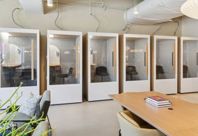 Row of private white soundproof phone booths with glass doors for focused work.