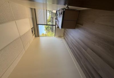 Empty private office with wood-style flooring and a large window overlooking trees.