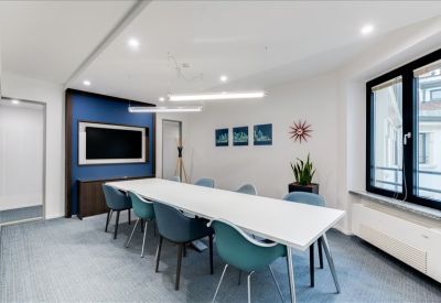 Conference room featuring a blue accent wall, wall-mounted screen, and teal seating.