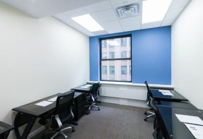 Private office suite with dark wood desks and a view of a blue accent wall.