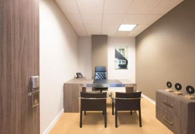 Compact private office featuring a dark wood desk and an accent wall.
