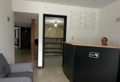 Portrait view of a black reception desk with a waiting area sofa and hallway access.