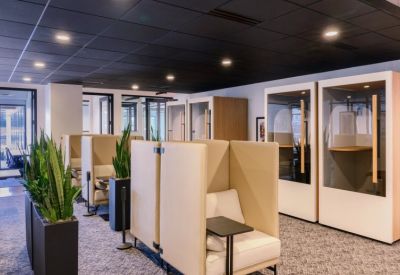 Breakout lounge with high-backed privacy booths, potted plants, and dark ceilings.