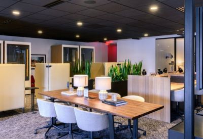 Shared workspace with a long wooden table, desk lamps, and soundproof phone booths.