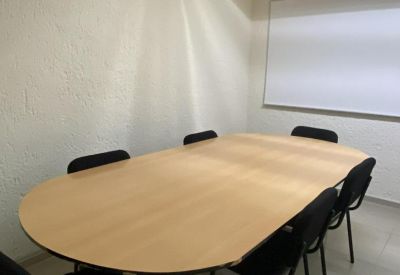 Meeting room with a large oval wood-topped table and black chairs.