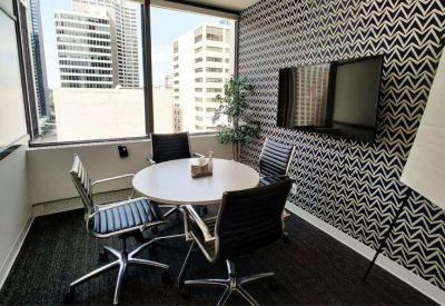 Small meeting room with a round table and chairs against a bold chevron-patterned feature wall.