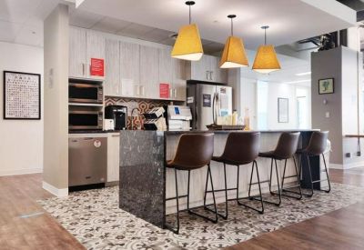 Modern kitchen and bar area with patterned floor tiles and three yellow pendant lights.