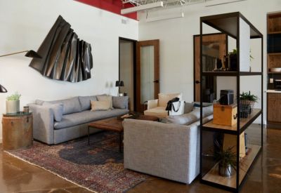 Stylish lounge area with a grey sofa, vintage-style rug, and unique wall sculpture.