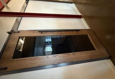 Entrance with a heavy wooden door featuring a glass pane and industrial hardware.