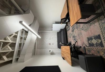 Modern workspace featuring a patterned rug, wooden desks, and industrial lighting.