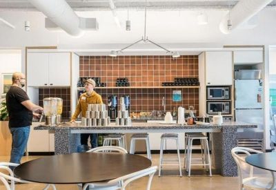 Modern communal kitchen and cafe area with a tiled backsplash and stone island.