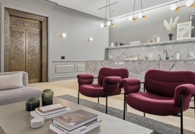 Modern lounge area with burgundy velvet armchairs and a marble-clad kitchenette bar.