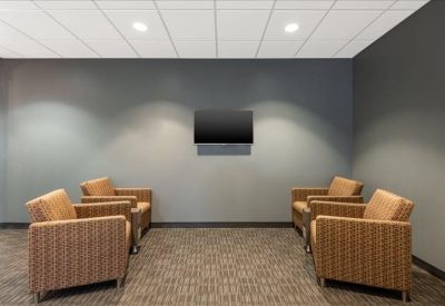 Comfortable lounge area with four armchairs and a wall-mounted TV.