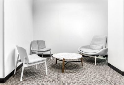 Small breakout area with modern white chairs and a circular coffee table.