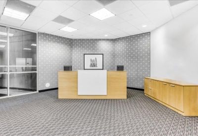 Professional reception desk with wood finishes and patterned grey carpet.