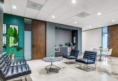 Lounge area with blue leather chairs, a marble floor, and a small coffee bar.