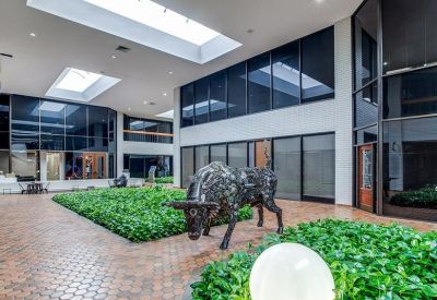 Sunlit communal courtyard with manicured green space and a bull statue.