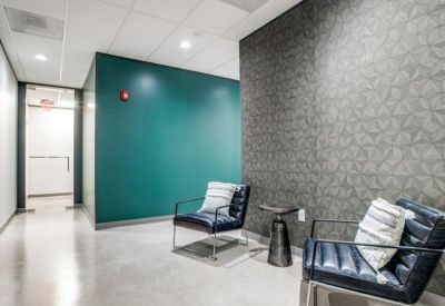 Waiting area with stylish blue armchairs and a patterned grey feature wall.