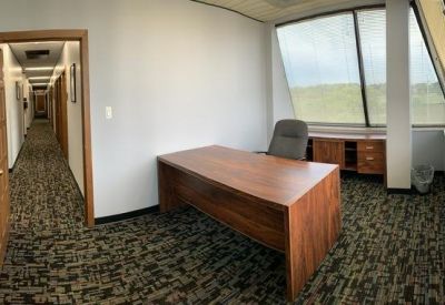 Private office featuring a rich wood desk and a view of the corridor.