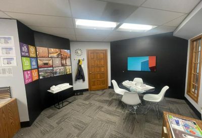 Modern meeting room with a round table, white chairs, and a black accent wall.