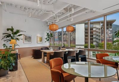 Lounge area featuring orange pendant lights, velvet chairs, and large windows with city views.