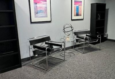 Lounge area with modern black chairs and colorful abstract wall art.