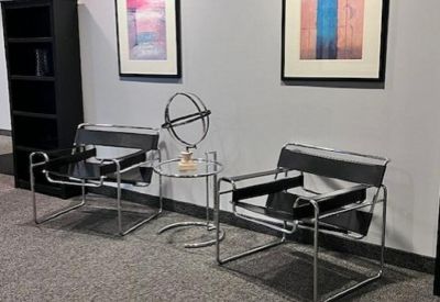 Seating area with chrome-frame chairs and an orbital sculpture on a side table.
