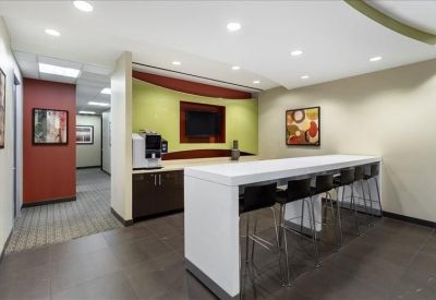 Employee break area with a white kitchen island, coffee machine, and colorful accent walls.