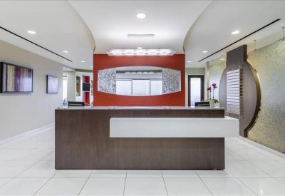 Professional reception area with a dark wood desk and a bold orange feature wall.
