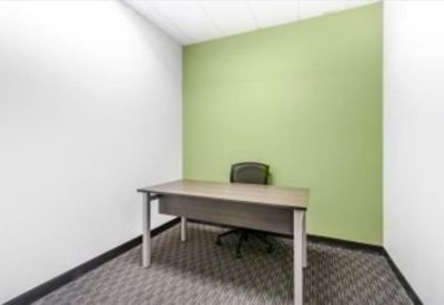 Private single-person office suite featuring a green feature wall and grey carpet.