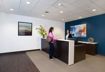 Modern reception area featuring a dark wood desk, blue accent wall, and colorful abstract artwork.