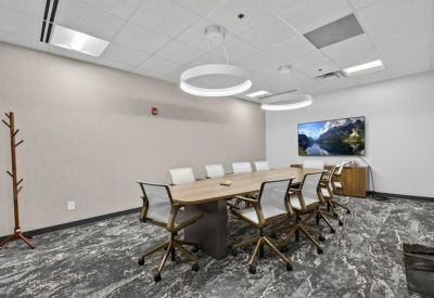 Professional boardroom with a large wooden table and circular pendant lights.