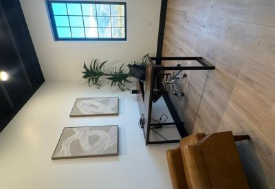 Private office with a wood desk, potted plant, and abstract wall art.