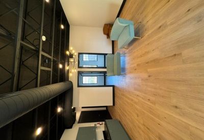 Wide view of a modern lounge featuring exposed ceiling ducts and light wood floors.
