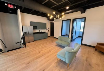 Spacious communal area at 352 South 2000 West with teal armchairs, a kitchenette, and modern lighting.