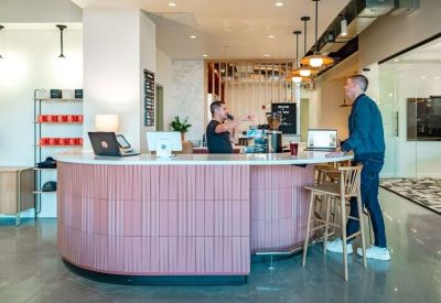 Curved pink-tiled reception desk with a white countertop and a person standing behind the counter.