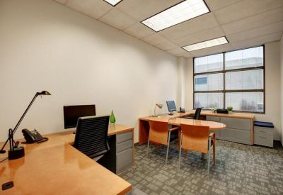 Private office suite featuring a wooden L-shaped desk and guest seating area.