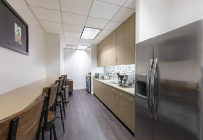 Narrow galley kitchen with light wood cabinets and a stainless steel refrigerator.