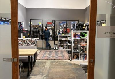 Entrance to a bright workspace through wooden sliding doors, showing a reception area and retail display.