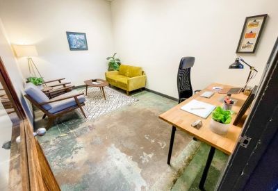 Private office suite featuring mid-century modern furniture, a yellow velvet sofa, and a wooden desk.