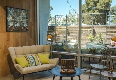 Bright breakout area with a cream sofa, colorful pillows, and large window overlooking trees.