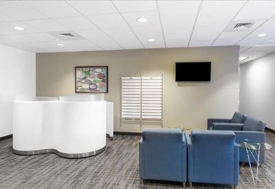 Building lobby featuring a modern curved white reception desk and blue armchairs.
