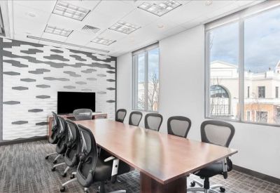 Bright conference room with a large wooden table and grey ergonomic chairs.